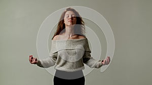 A young girl is practicing yoga and relaxing during lunch break at workplace. A lady student shuts eyes, takes a deep