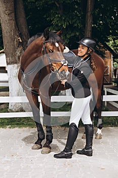 Young girl preparing to become a riding instructor taking care and talking to a horse on a hot autumn day