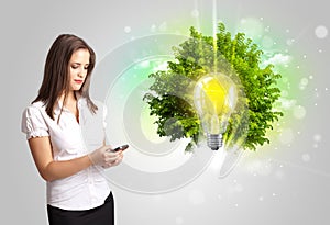 Young girl presenting idea light bulb with green tree