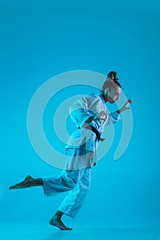 Young girl professional judoist isolated on blue studio background in neon light. Healthy lifestyle, sport concept.