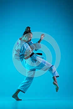 Young girl professional judoist isolated on blue studio background in neon light. Healthy lifestyle, sport concept.