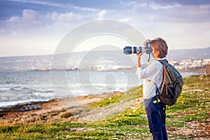 Young girl professional photographer on the beach with a camera