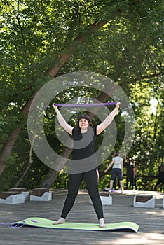 Young girl pump up arms with an expander. Fitness in the park. Expander training for beginners. Individual training