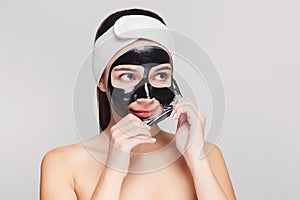 Young girl with purifying black face mask photo