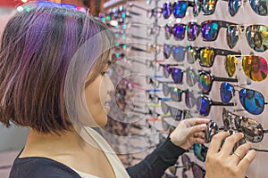 Young girl with purple hair choosing glasses