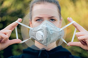 Young girl putting on anti-virus anti-smog mask on her face