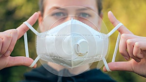 Young girl putting on anti-virus anti-smog mask on her face