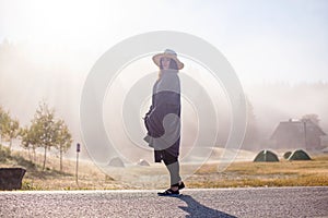 Young girl in a raincoat in the morning at dawn against a background of fog and mountains