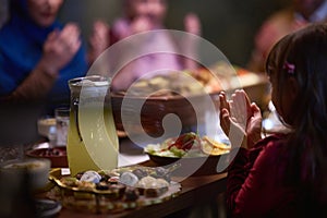 A young girl raises her hands in prayer as she prepares for her iftar meal during the holy month of Ramadan, embodying