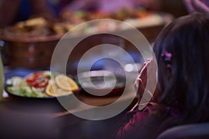 A young girl raises her hands in prayer as she prepares for her iftar meal during the holy month of Ramadan, embodying