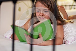 Young girl reading in bed, shallow depth