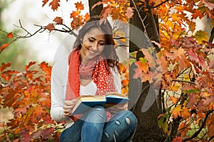 Young girl reading book in autumn park
