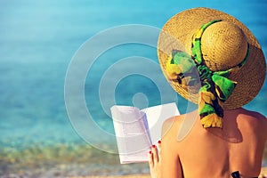 Young girl, reading a book at the beach