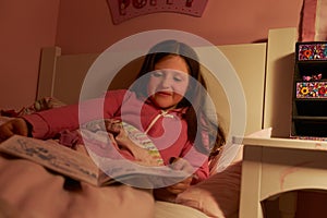 Young Girl Reading Book In Bed At Night