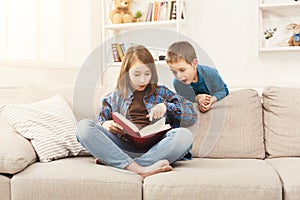 Young girl reading book for her brother