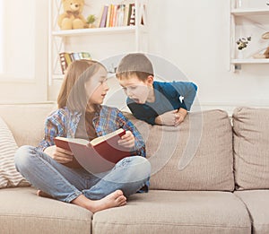 Young girl reading book for her brother