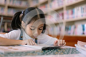 A young girl is reading a book in a library