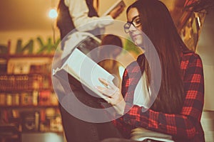 Young girl reading book in library.