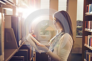 Young girl reading book at library over beautiful sunshine