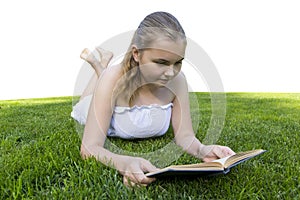 Young girl reading book while lying in grass