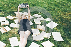 Young girl reading a book while lying in the grass. A girl among the books in the summer garden