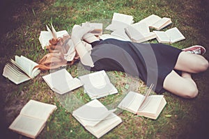 Young girl reading a book while lying in the grass. A girl among the books in the summer garden