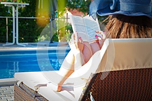 Young girl reading book near swimming pool.concept summer