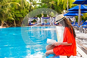 Young girl reading book relaxing in swimming pool
