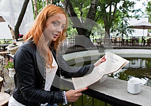 Young girl reading a newspaper in cafeteria