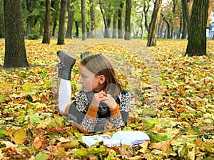 Young girl reads a book in the autumn park