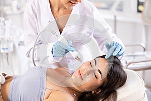 Young girl receiving facial procedure with hydrogen and oxygen ions attachment