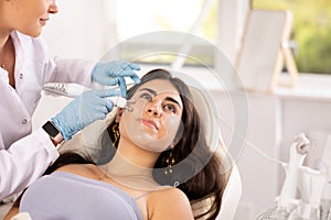 Young girl receiving facial radiofrequency procedure to tighten skin