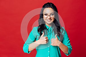 A young girl on a red background shows with her fingers that she is in a good mood