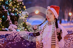 Young girl in a red cap standing at the Christmas tree on Christ