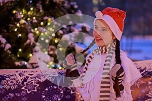 Young girl in a red cap standing at the Christmas tree on Christ