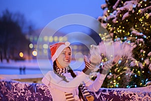 Young girl in a red cap stands near a Christmas tree. She throws