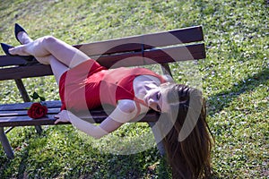 Young girl with red dress lying on the bench in sexy pose