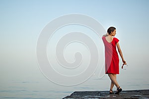Young girl in red dress on the sea and blue background, summertime, travelling concepts