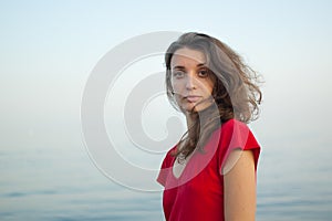 Young girl in red dress on the sea and blue background, summertime, travelling concepts