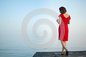 Young girl in red dress on the sea and blue background, summertime, travelling concepts