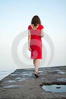 Young girl in red dress on the sea and blue background, summertime, travelling concepts