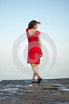 Young girl in red dress on the sea and blue background, summertime, travelling concepts