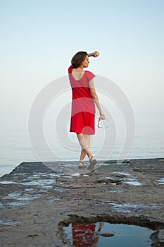 Young girl in red dress on the sea and blue background, summertime, travelling concepts
