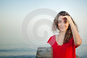 Young girl in red dress on the sea and blue background, summertime, travelling concepts