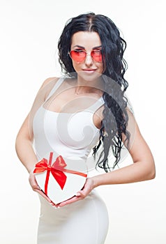 Young girl with red heart-shaped gift box in white dress on white background