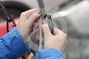 Young girl with red nails is preparing to put a new car windshield wiper brush