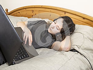 Young Girl Relaxed in Bed while on her Computer