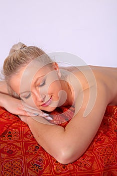 A young girl relaxes in a spa, lying on her stomach with her eyes closed