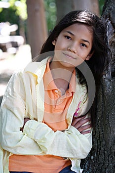 Young girl relaxing against tree