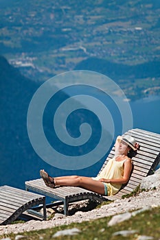 Young girl relaxing on a chaise longue in mountains Dachstein Krippenstein in Austria